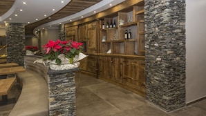 Una zona de bar con armarios de madera y detalles de piedra, que presenta un gran arreglo floral y un banco curvo.