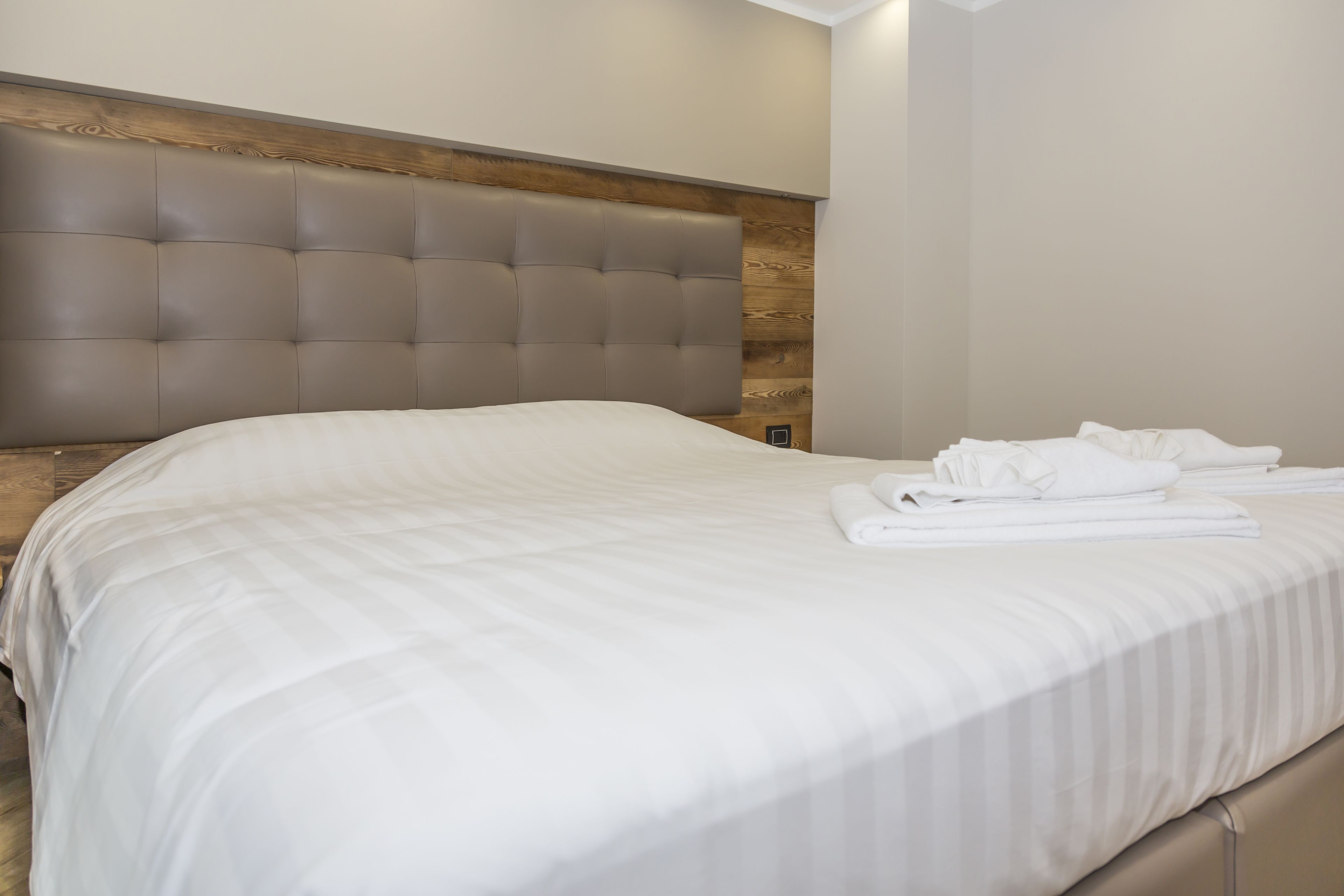 A neatly made bed with white linens and a tufted headboard.