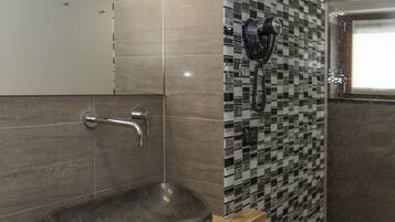 Une salle de bain avec un meuble-lavabo en bois, un évier en pierre et un mur recouvert de carreaux.