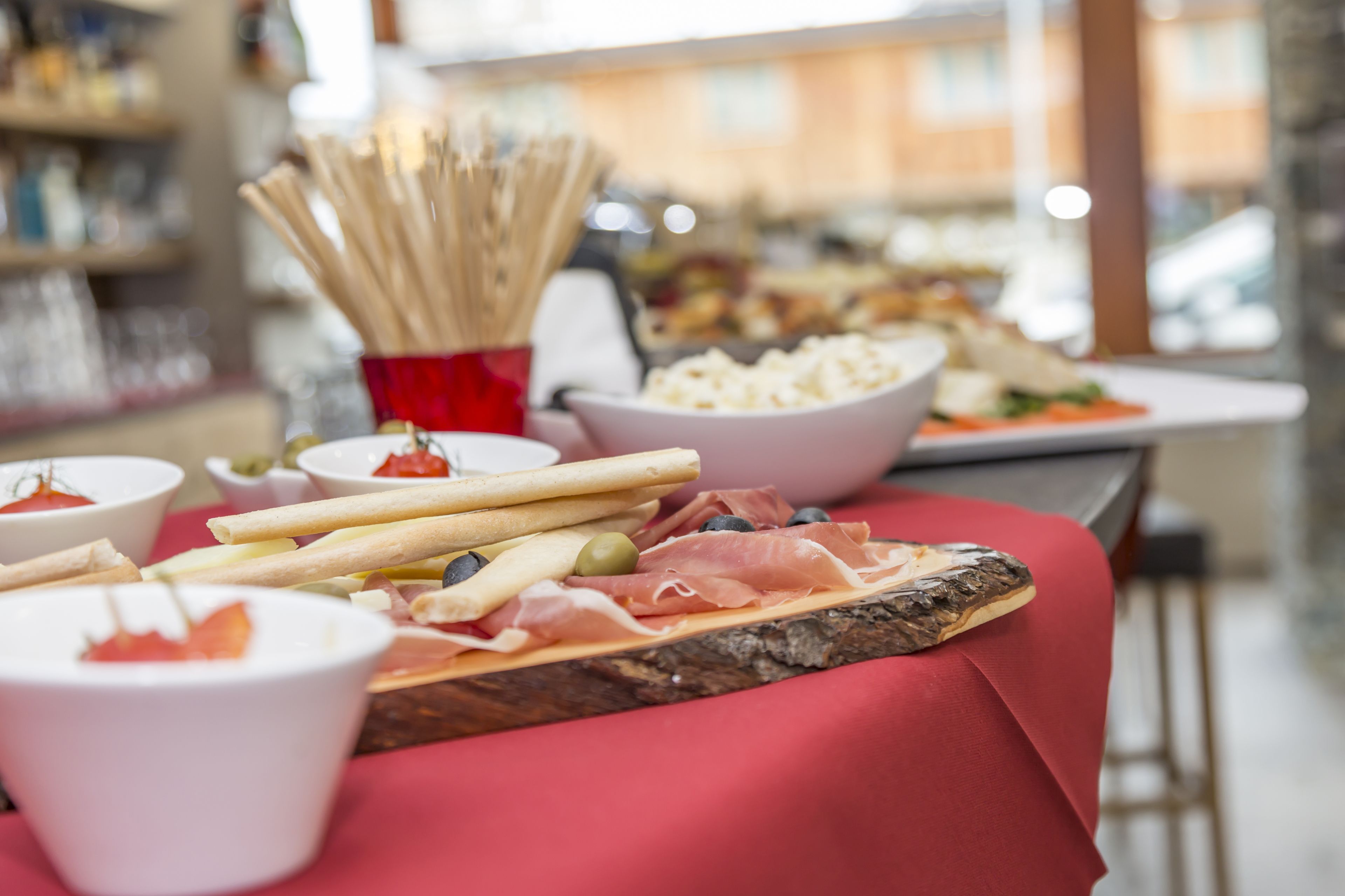 Un tavolo da buffet con diversi alimenti, tra cui grissini, olive e salumi.