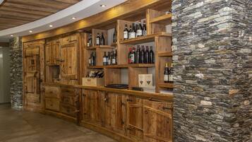 Una zona de bar con armarios de madera y paredes de piedra, con estantes que exhiben botellas y copas.