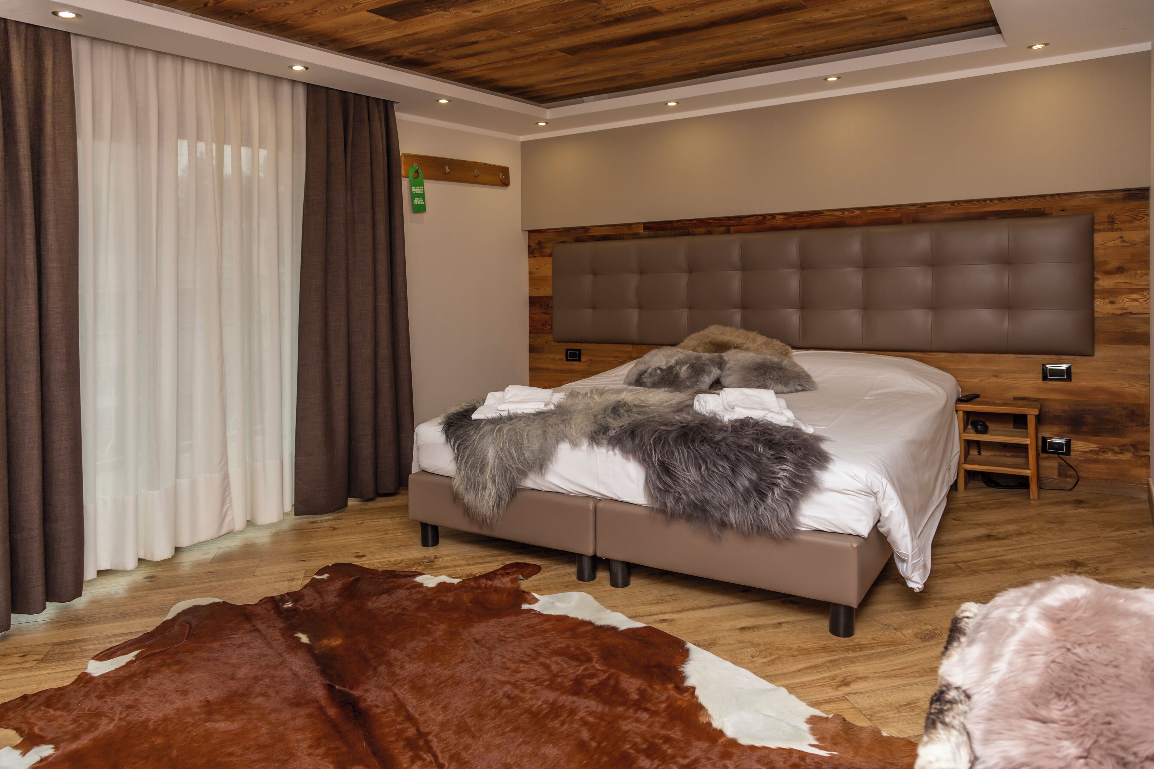 Une chambre moderne avec un grand lit, une tête de lit en bois et un tapis en peau de vache.