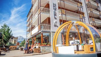 Un hotel con terraza exterior, cubierta de madera y vistas a la montaña.
