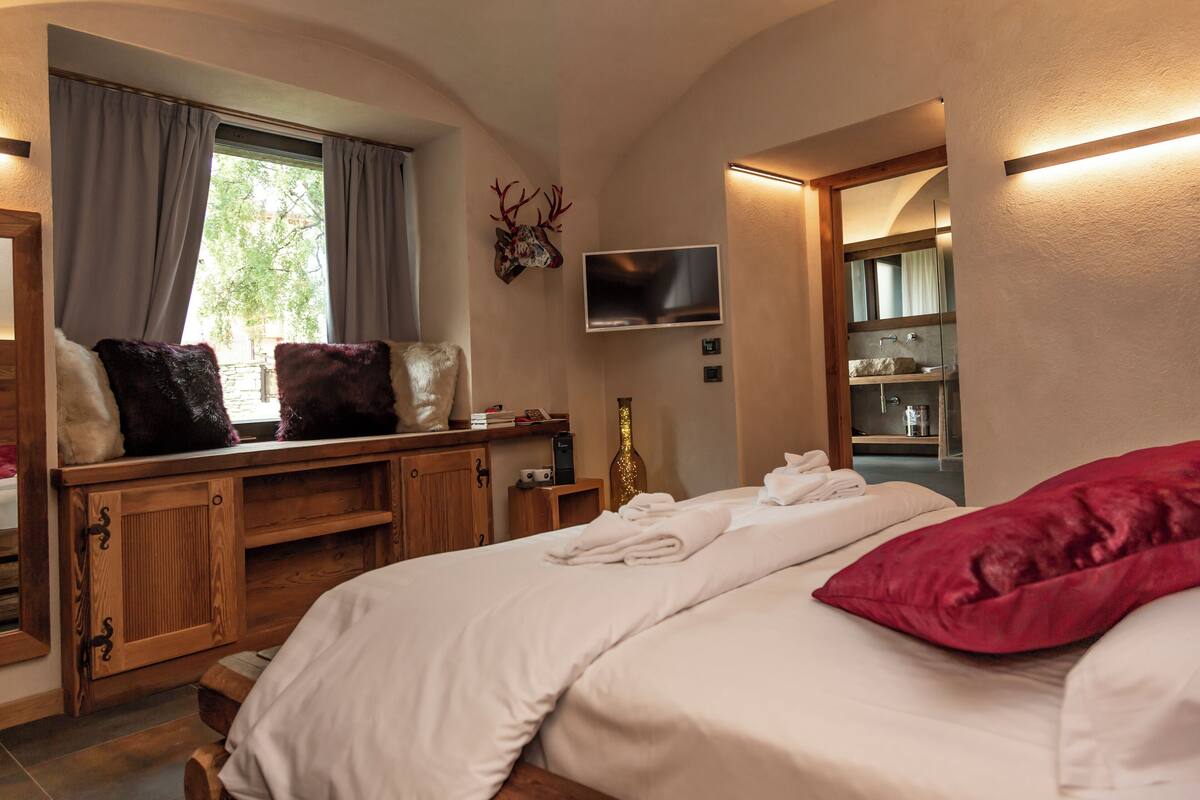 Une chambre à coucher avec un lit, une télévision, une fenêtre avec des rideaux et une armoire en bois.
