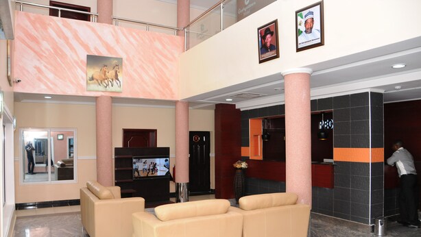 A hotel lobby with a reception desk, a TV, and a seating area with two sofas.