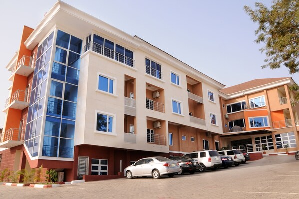 A multi-story building with a parking area in front. - Georgetown Hotel (Abuja)