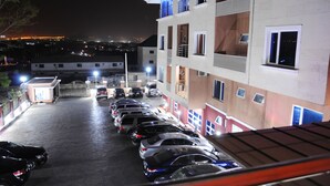 A parking lot with multiple cars parked in front of a building with balconies and windows.