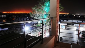 A balcony with a metal railing overlooking a cityscape at night.