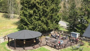 A gazebo with a curved roof, surrounded by a wooden deck with outdoor seating and potted plants. - Hotel Tři růže (Spindleruv Mlyn)