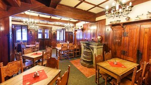 A traditional dining room with wooden furniture, chandeliers, and a fireplace. - Hotel Tři růže (Spindleruv Mlyn)