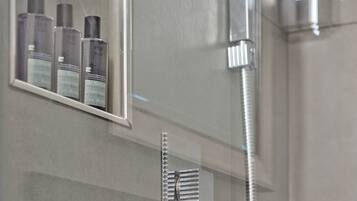 Une salle de bain avec une douche à parois de verre, un miroir et une étagère contenant des articles de toilette.