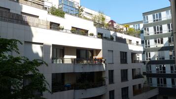 Ein mehrstöckiges Wohngebäude mit Balkonen, großen Fenstern und etwas Grün.