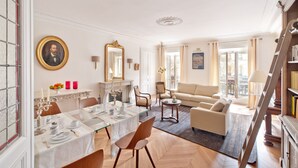 A spacious living room with a dining area, a sofa, and a staircase. - My Home For You B&B (Paris)
