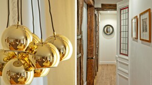 A hallway with a wooden door, a round mirror, and framed pictures on the wall. - My Home For You B&B (Paris)