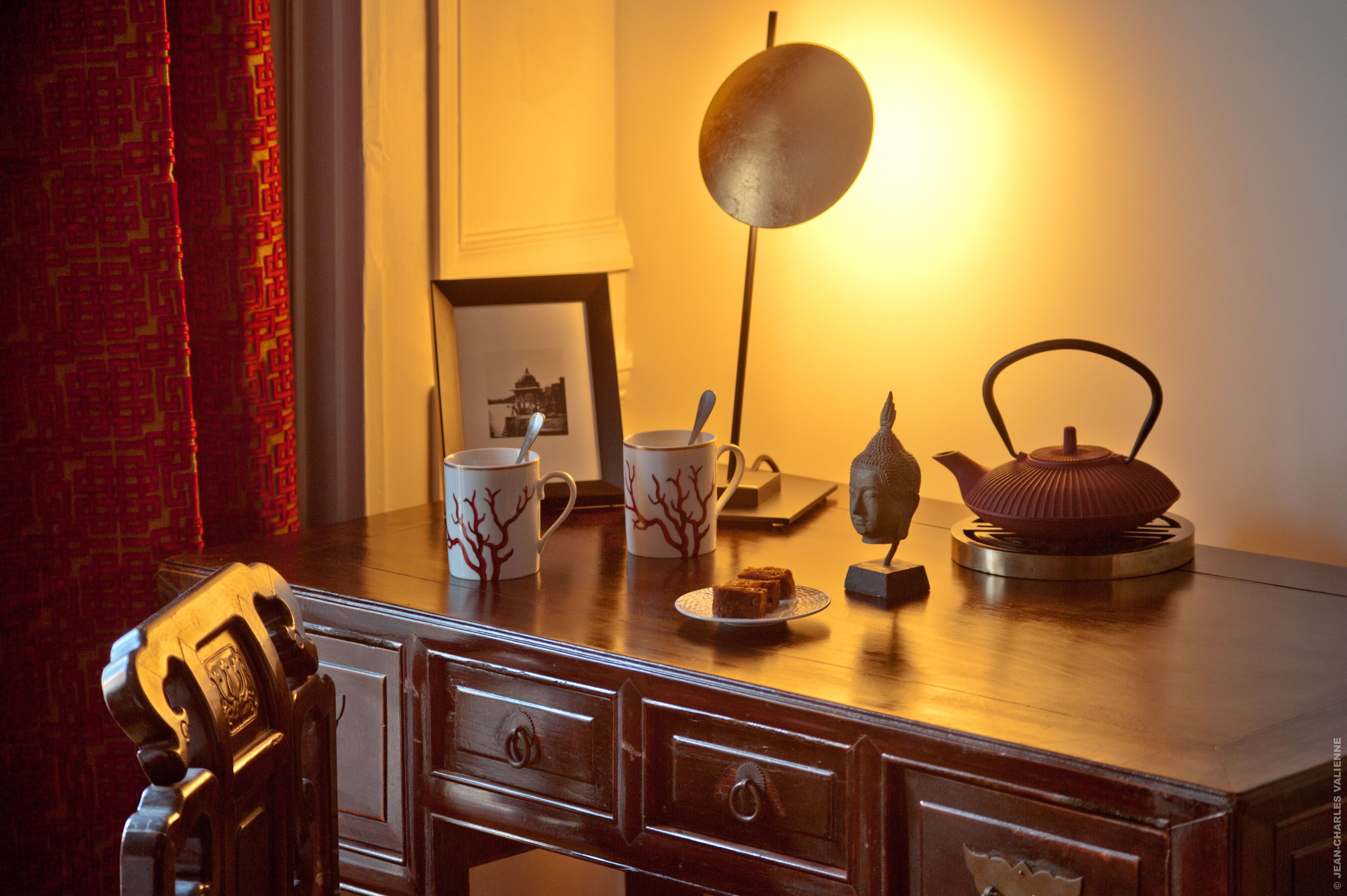 A wooden desk with a lamp, a framed picture, and decorative items.