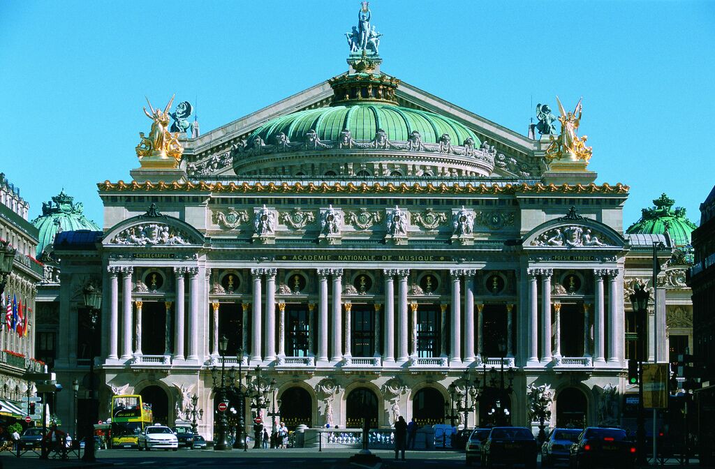 A grand classical building with a prominent green dome and statues on the facade.