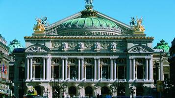 A grand classical building with a prominent green dome and statues on the facade.