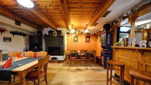 A wooden interior with a dining table, chairs, and a bar area. - Hotel Výsluní (Spindleruv Mlyn)