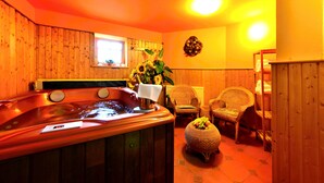A wooden interior with a hot tub, wicker chairs, and a small table with fruit. - Hotel Výsluní (Spindleruv Mlyn)