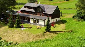 A large, two-story house with a sloped roof, surrounded by a lush green landscape. - Hotel Výsluní (Spindleruv Mlyn)