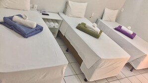 A hotel room with three beds, each with a white mattress and pillows. There are towels in various colors on each bed. - Acapú Hotel (Rio Verde)