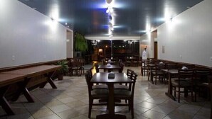A restaurant with a long counter, multiple tables, and chairs. - Acapú Hotel (Rio Verde)