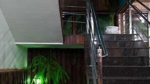 A modern interior with a staircase, a green artificial garden, and a seating area with wooden benches. - Acapú Hotel (Rio Verde)