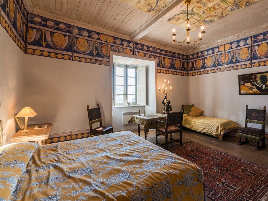 Een klassieke kamer met een bed, een bureau en een stoel. Er is een raam en een deur.