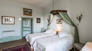 A bedroom with two beds, a wooden floor, a red rug, and a green door.