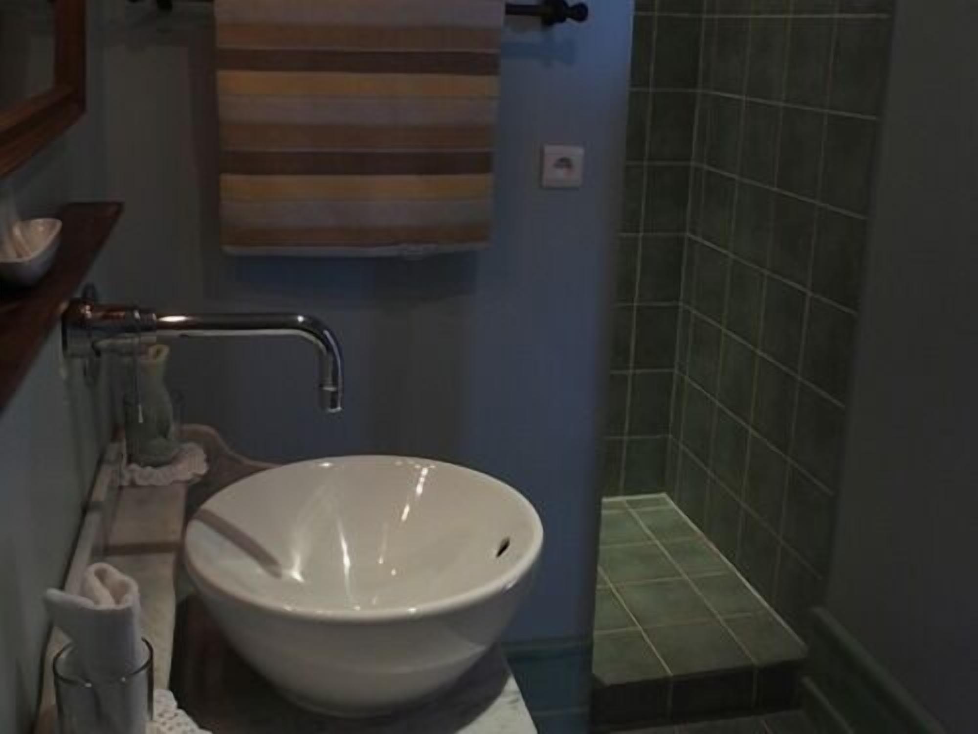 A bathroom with a white sink, a towel hanging on the wall, and a shower area with tiled walls.