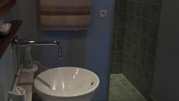 A bathroom with a white sink, a towel hanging on the wall, and a shower area with tiled walls.