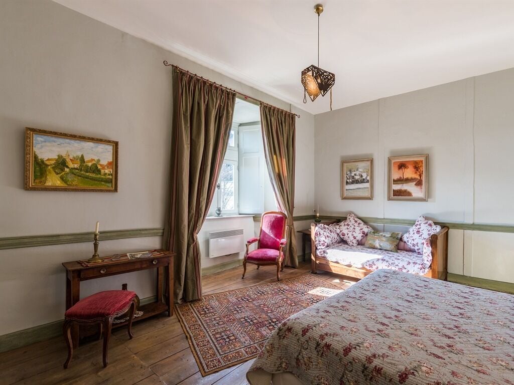 Une chambre à coucher avec un lit, une chaise, une table et deux tableaux accrochés au mur.