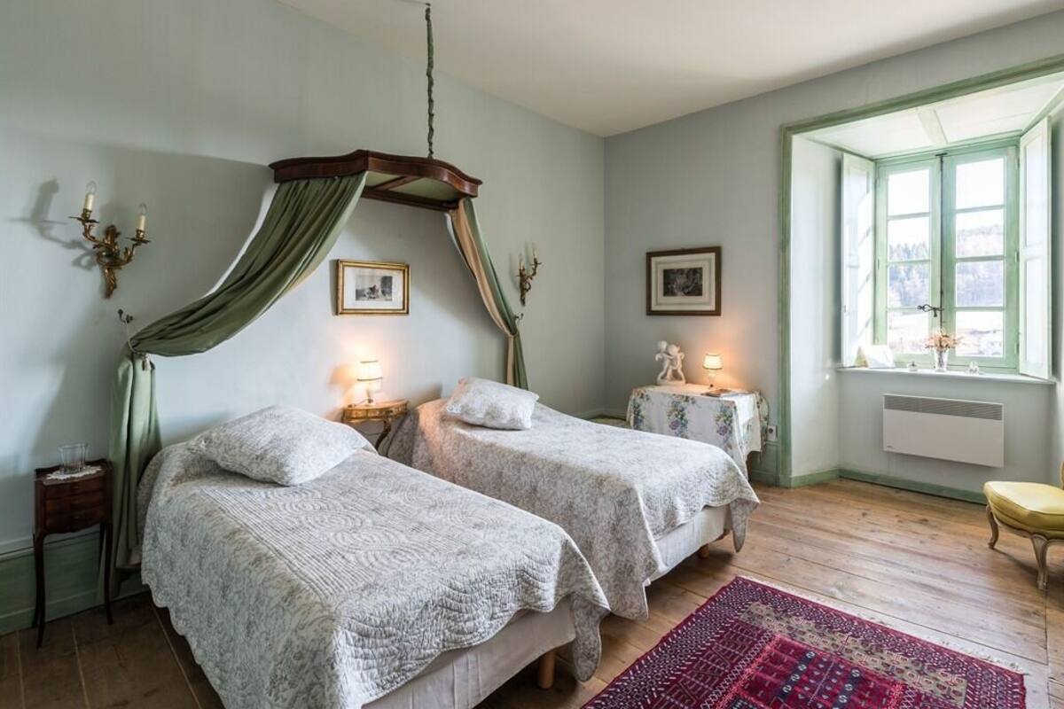 A bedroom with two beds, a canopy bed, a window with a view, and a red rug.