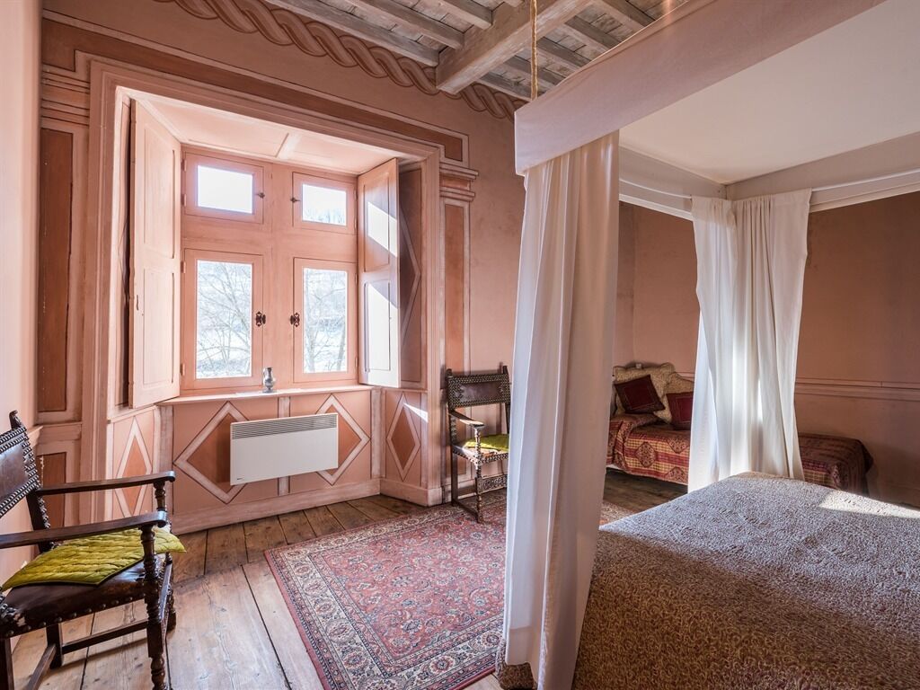 A room with a large window, a bed, a chair, and a radiator.
