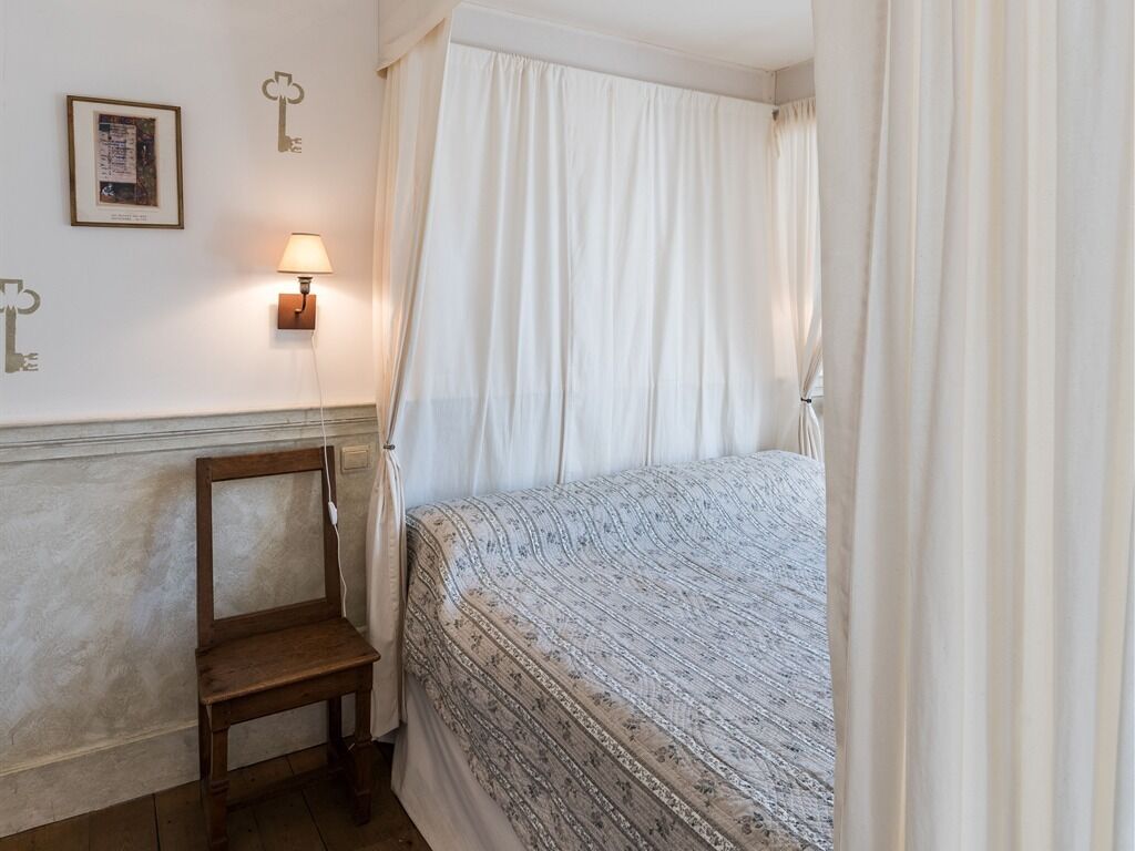 A bedroom with a bed, a nightstand, a lamp, and a chair.