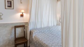 A bedroom with a bed, a nightstand, a lamp, and a chair.