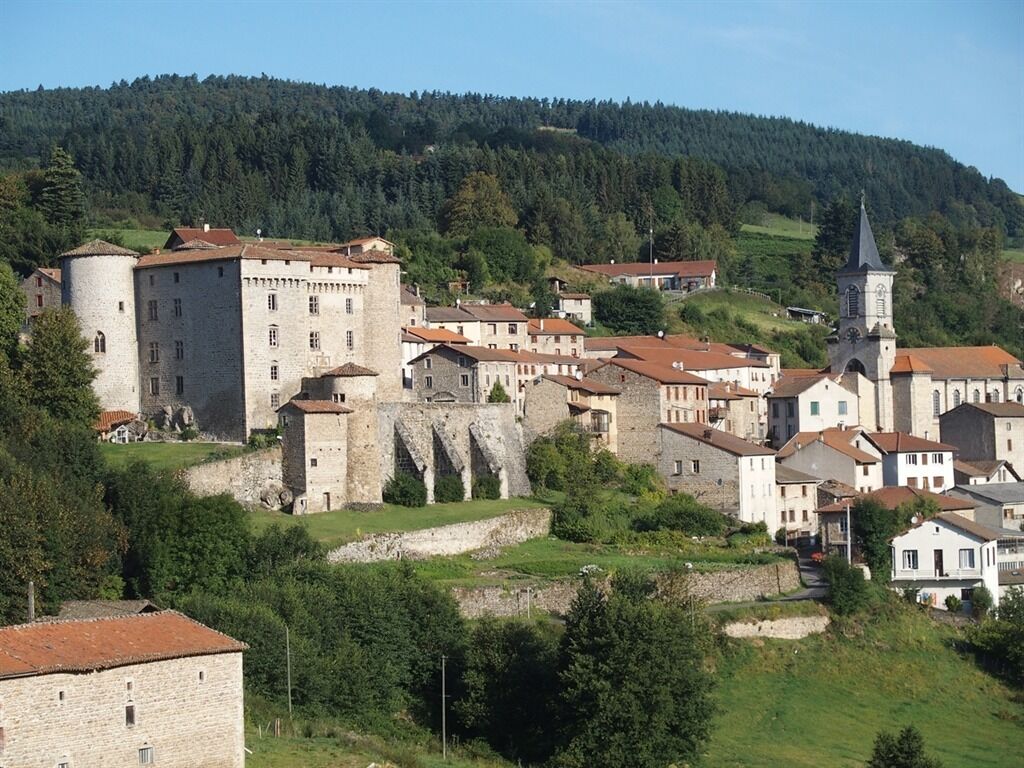 Uma cidade histórica com edifícios de pedra, um castelo imponente e uma igreja.