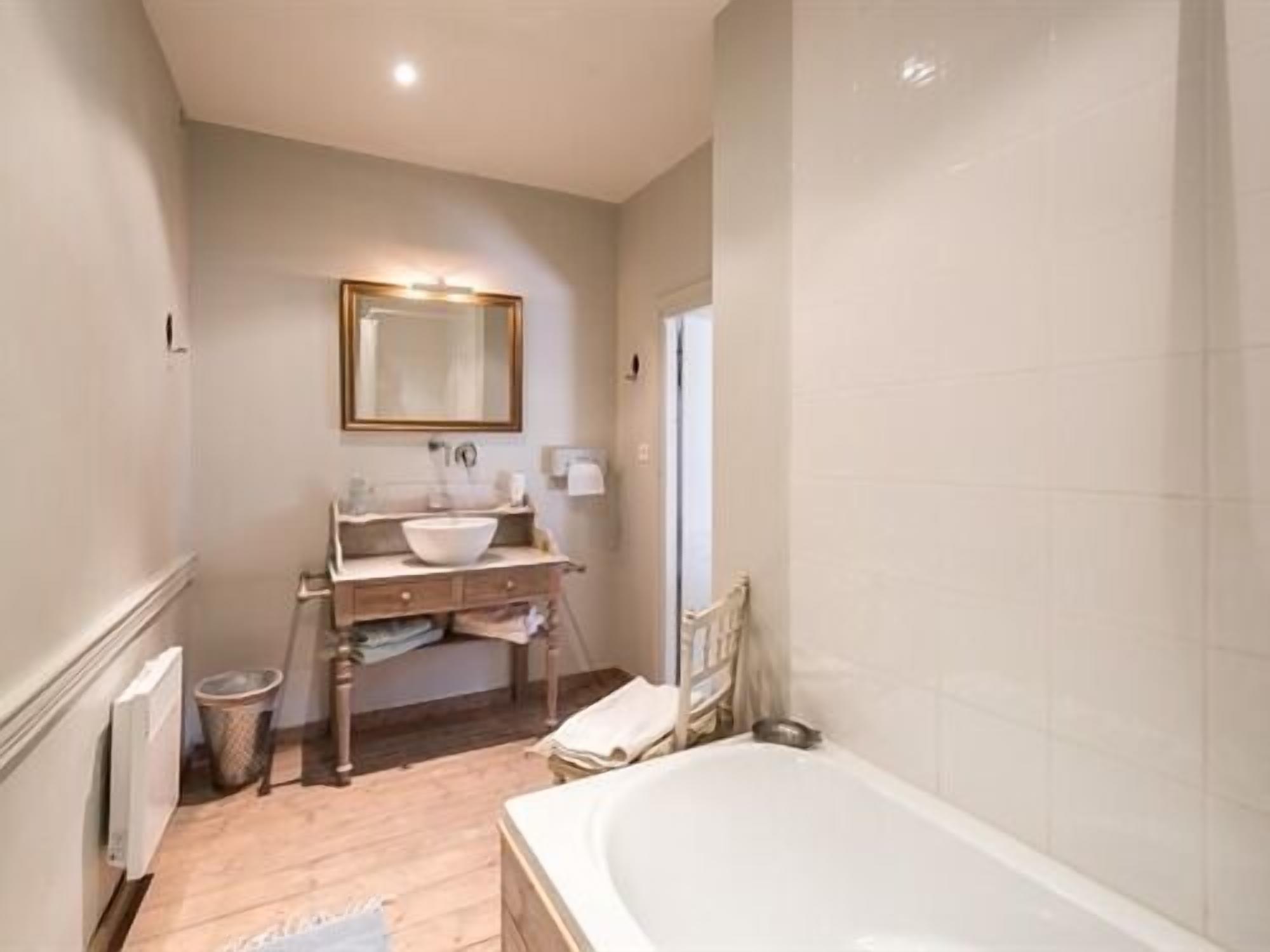 A bathroom with a bathtub, a sink with a mirror, and a radiator.