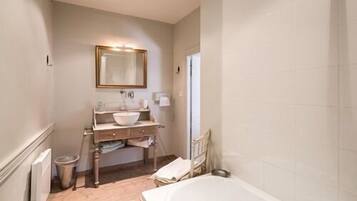 A bathroom with a bathtub, a sink with a mirror, and a radiator.