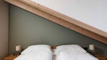 Ein Schlafzimmer mit zwei Einzelbetten, Holz-Kopfteilen und Nachttischlampen.