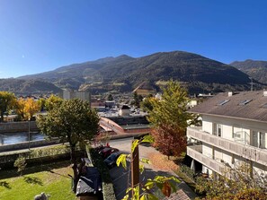 Zona residencial con vistas a montañas, una carretera pavimentada y coches aparcados.