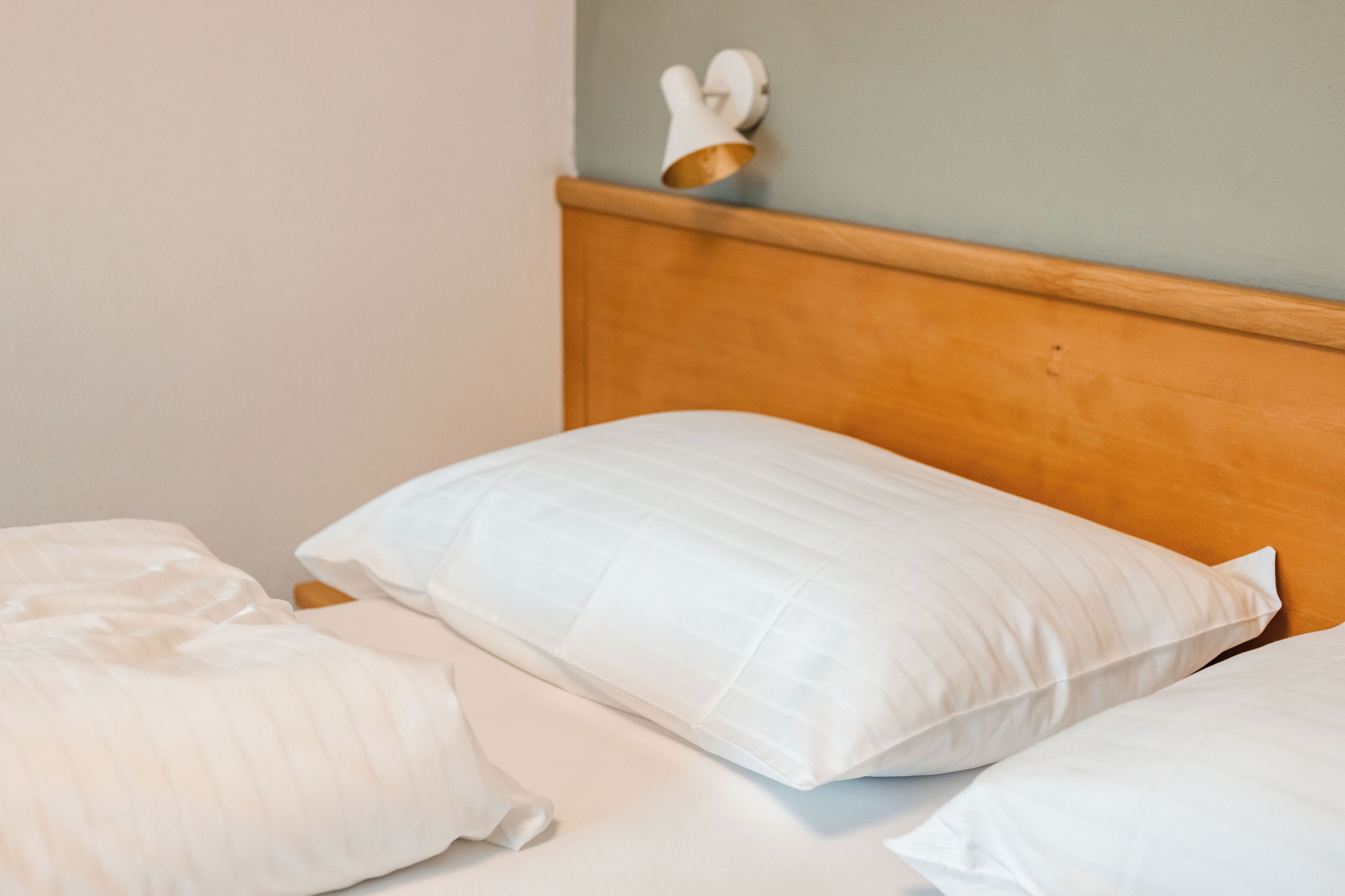 Een bed met witte beddengoed en een houten hoofdbord.