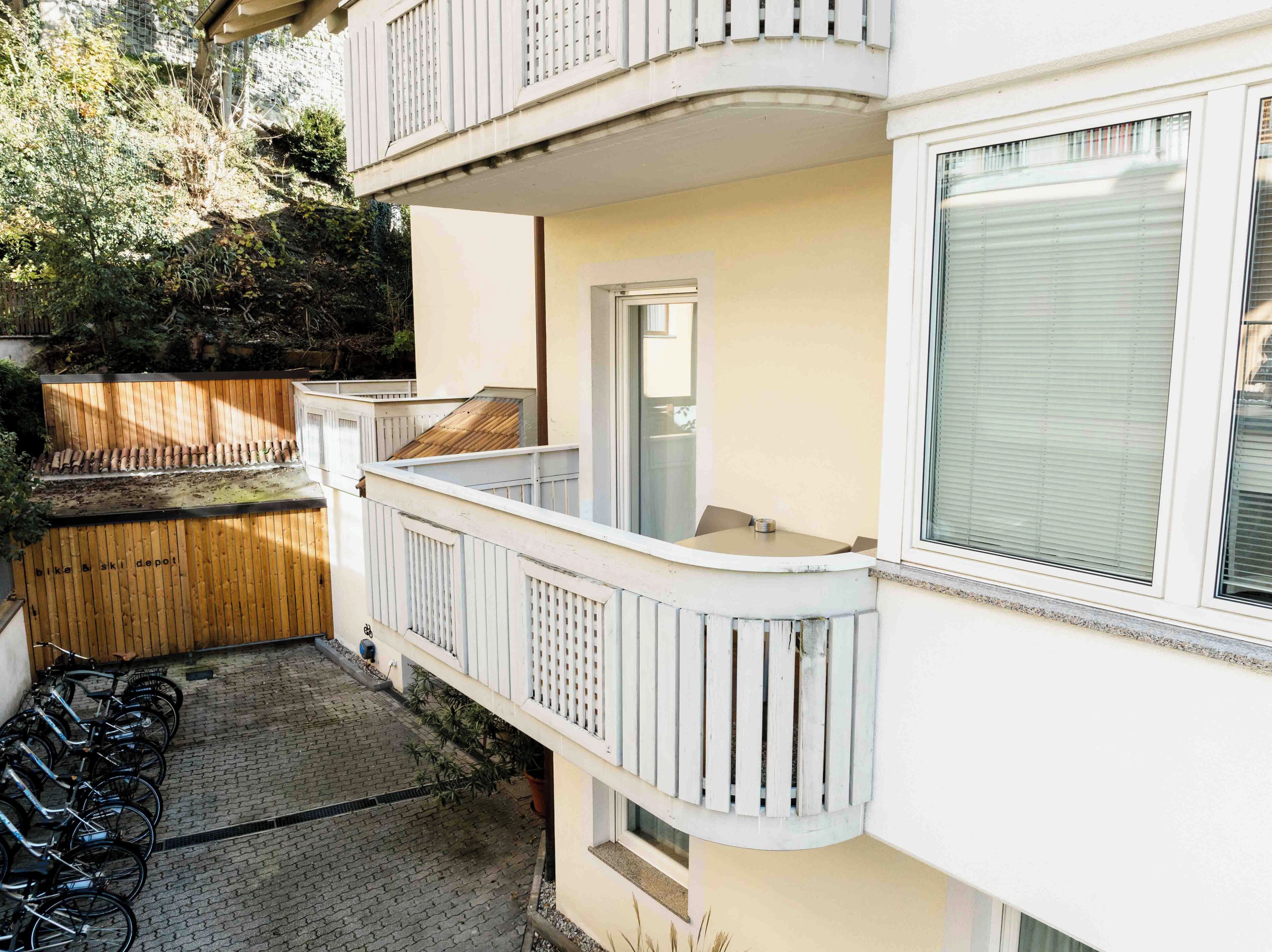 A building with a balcony, a door, and a window with blinds.