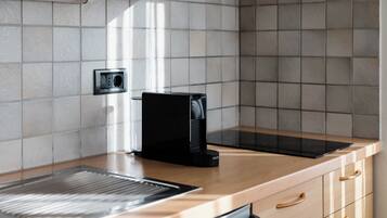 A kitchen with a built-in coffee maker, a kettle, and a toaster on the countertop.