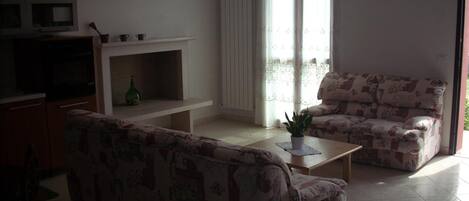 Una sala de estar con sofá, una mesita y un televisor sobre un mueble.