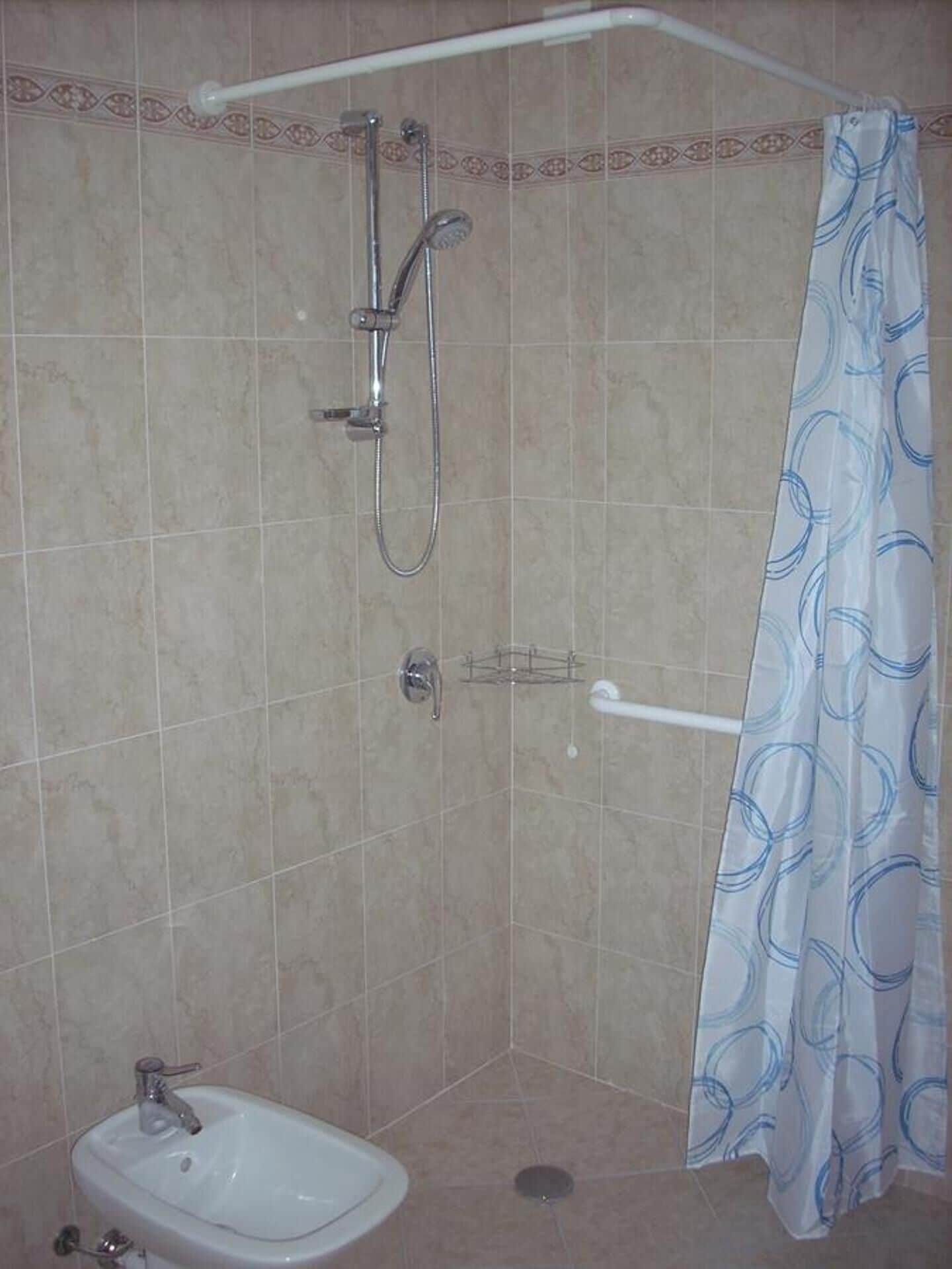 A bathroom with a shower, a sink, and a towel rack.
