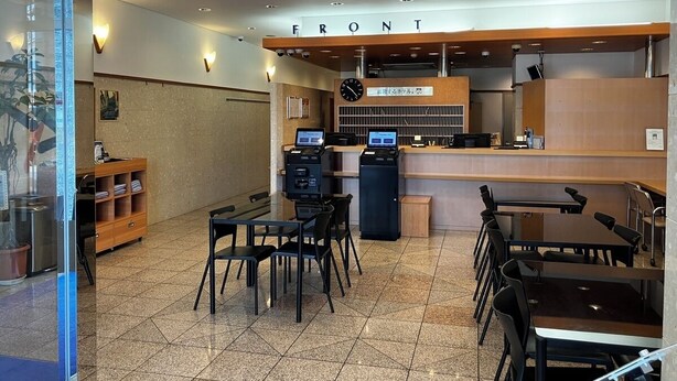Un interior de restaurante moderno con un letrero que dice 'FRONT', zona de estar y una barra con una pantalla de menú.