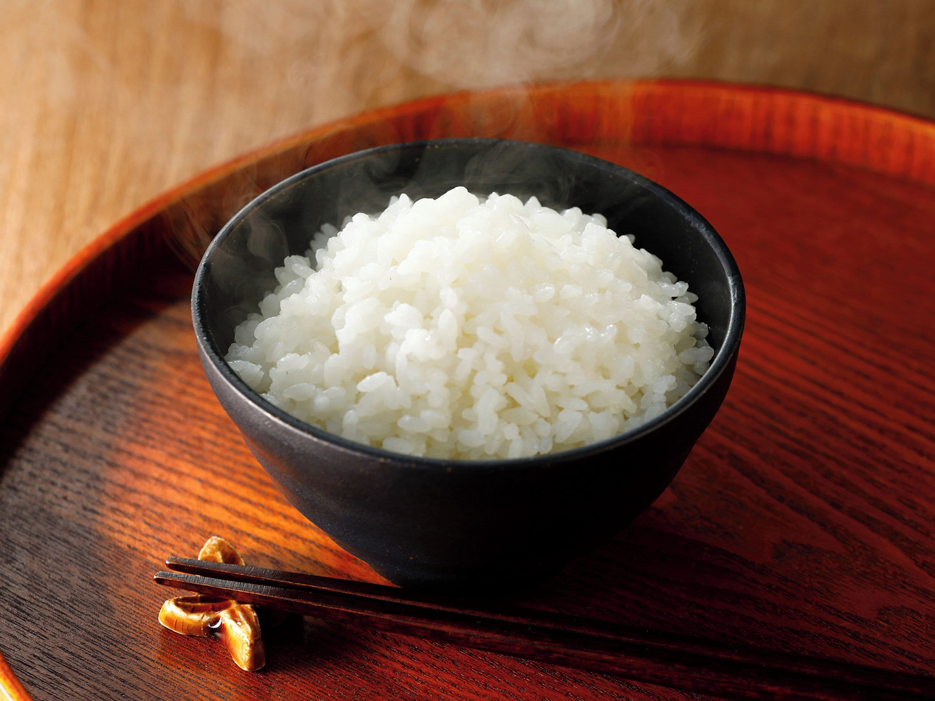 Un tazón de arroz blanco sobre una bandeja de madera.