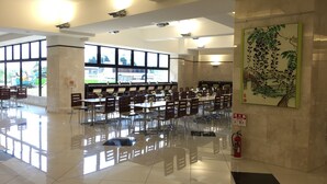 Amplio espacio interior con varias mesas y sillas, ventanas grandes y un extintor en el suelo.