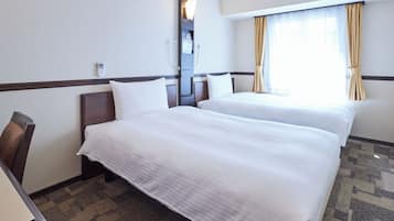 Une chambre d’hôtel avec deux lits, un bureau et une fenêtre avec des rideaux.
